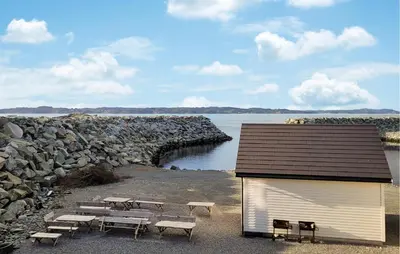 a building with benches next to a body of water at Awesome Home In Sveio in Sveio