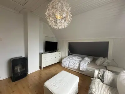 a bedroom with a bed and a television and a chandelier at Koselig hus med stor og solrik hage in Lillehammer