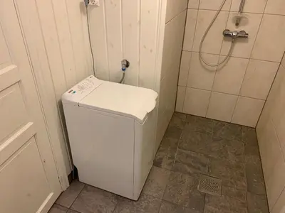 a small bathroom with a white refrigerator and a shower at Rikstaddal in Kalvhagen