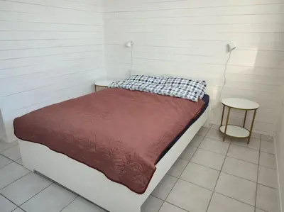 a small bedroom with a bed and a stool at Biri nær Gjøvik ,Hamar og Lillehammer apartments in Gjøvik