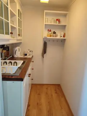 a small kitchen with white cabinets and a wooden floor at Biri nær Gjøvik ,Hamar og Lillehammer apartments in Gjøvik