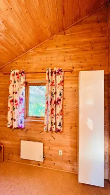 a room with a wooden wall with a window and a refrigerator at Fjordhytte-3 in traumhafter Lage 100 Meter vom Hardangerfjord, Motorboot mietbar in Ænes