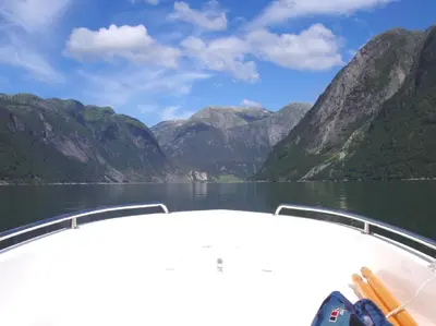 a boat on a lake with mountains in the background at Fjordhytte-3 in traumhafter Lage 100 Meter vom Hardangerfjord, Motorboot mietbar in Ænes