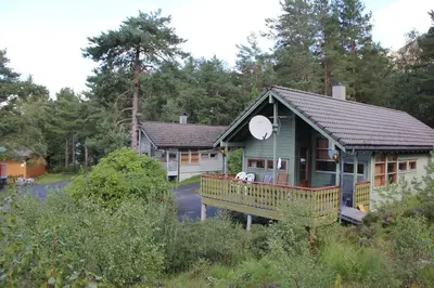 a house with a porch in the woods at Fjordhytte-40 im Vestland - Hordaland nahe Rosendal in Rosendal