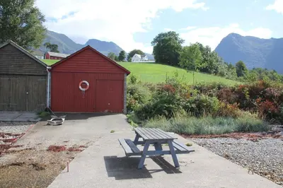 a picnic table in front of a red shed at Fjordhytte-41 mit mietbarem 9,9 PS Motorboot am Hardangerfjord in Rosendal