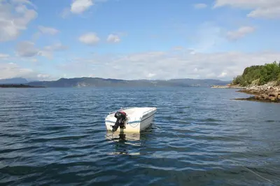 a boat in the middle of a body of water at Fjordhytte-41 mit mietbarem 9,9 PS Motorboot am Hardangerfjord in Rosendal