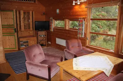 a living room with chairs and a table and a tv at Fjordhytte-41 mit mietbarem 9,9 PS Motorboot am Hardangerfjord in Rosendal