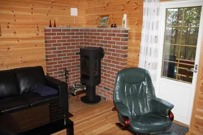 a living room with a leather chair and a fireplace at Fjordhytte-39 am Hardangerfjord, Motorboot mietbar in Rosendal