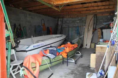 a boat in a garage with a table and a chair at Fjordhytte-38 bei Rosendal am Hardangerfjord in Rosendal