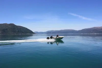 two people and a dog in a boat on the water at Fjordhytte-16 direkt am Sognefjord in Bjordal, mit mietbaren 9,9 PS bis 60 PS Motorbooten in Bjordal
