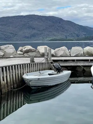 a small boat tied to a dock on the water at Fjordhytte-13 in Ænes