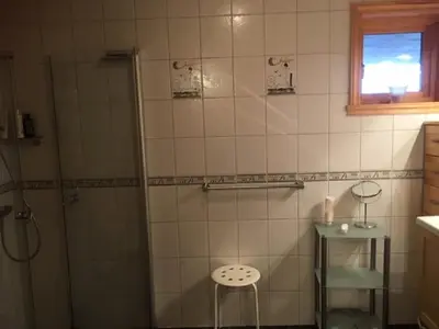 a bathroom with a shower and a stool in it at Fjordhytte-36 in Bøvågen