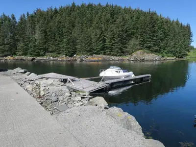 a boat is docked at a dock on a river at Fjordhytte-36 in Bøvågen
