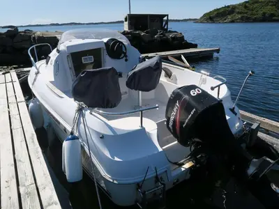 a white boat docked at a dock in the water at Fjordhytte-36 in Bøvågen