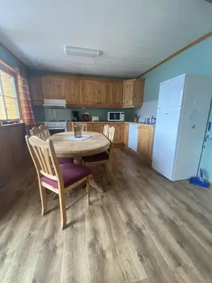 a kitchen with a table and chairs and a refrigerator at Fjordhytte-23 direkt am Sognefjord, mit mietbaren Motorbooten 9,9-60 PS in Bjordal