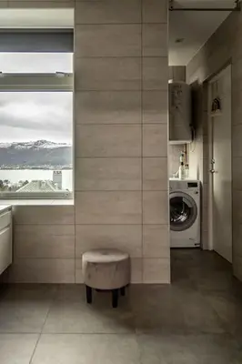 a bathroom with a washing machine and a stool at Fjord-view apartment in Ålesund
