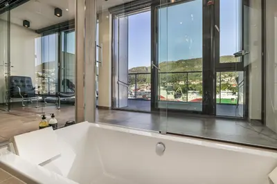 a large white bath tub in a room with windows at Nordnes Brygge in Bergen