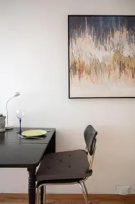 a black table with a chair and a painting on the wall at Studio in the city centre in Trondheim