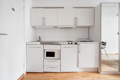 a white kitchen with white cabinets and a microwave at Studio in the city centre in Trondheim