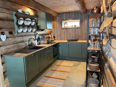 a kitchen with wooden walls and a sink and a counter at Rudland Gård - Unik gårdsovernatting i stabbur fra 1750 in Sør-Fron