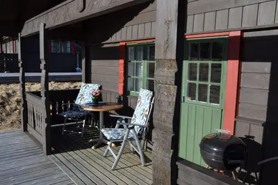 a porch of a house with two chairs and a table at Lifjellhytte 10 by Norgesbooking - cabin at Golsfjellet in Gol