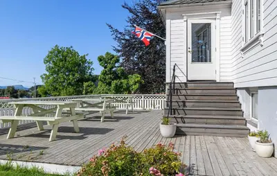 a wooden deck with benches and a flag on a house at Doktorgarden in Selje