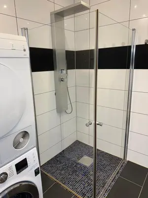 a shower with a glass door next to a washing machine at Duży apartament w centrum in Ålesund
