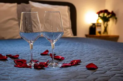 two wine glasses and red roses on a bed at KS Apartment Modern & cozy flat 20 min from Bergen centre in Espeland