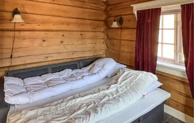 a bed in a room with a wooden wall at Beautiful Home In Øyer With Wifi in Øyer