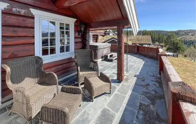 a patio with wicker chairs and a grill on a cabin at Beautiful Home In Øyer With Wifi in Øyer