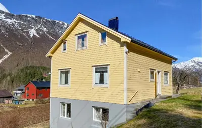 a yellow house on a hill with mountains in the background at 4 Bedroom Gorgeous Home In Valldal in Valldal