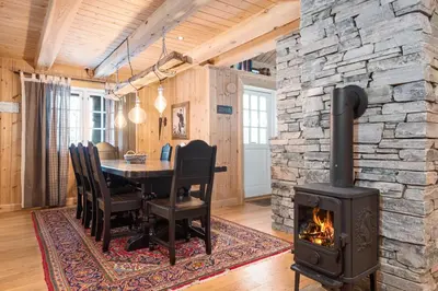 a fireplace in a dining room with a table and a stove at Trysilfjell sør 825 in Trysil