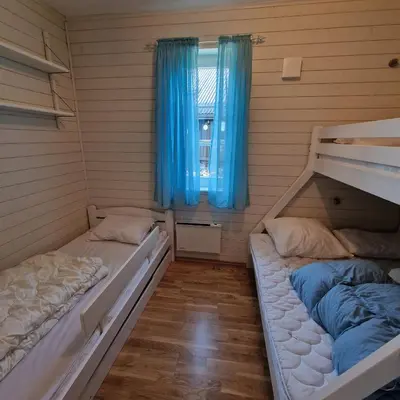 two beds in a room with blue curtains and a window at Family-friendly apartment for rent at Golsfjellet in Golsfjellet