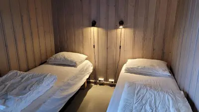 two beds in a room with wooden walls at Geilo Hytter & Camping in Geilo