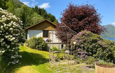 a garden with a house and a chair and flowers at Cozy Home In Austefjorden With Wifi in Austefjorden