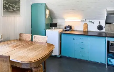 a kitchen with a wooden table and blue cabinets at Cozy Home In Austefjorden With Wifi in Austefjorden