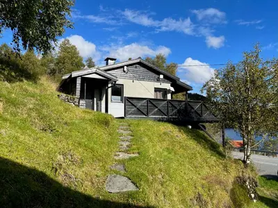 a house on top of a grassy hill at Cozy cabin with a view in Kvamseter