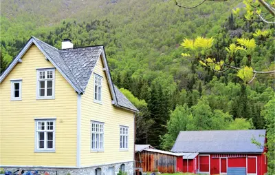a yellow house and a red barn in front of a mountain at 4 Bedroom Nice Home In Eidfjord in Eidfjord