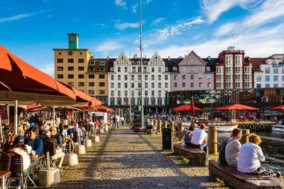a group of people sitting on benches next to a river at Dreggsalmenning 20 in Bergen