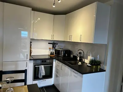 a kitchen with white cabinets and a sink at Apartment Lagunen with Terrace, Grill and Free Parking in Bergen