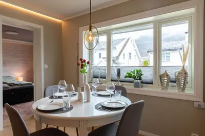 a dining room with a table and chairs and a window at Huset på Plassen in Sogndal