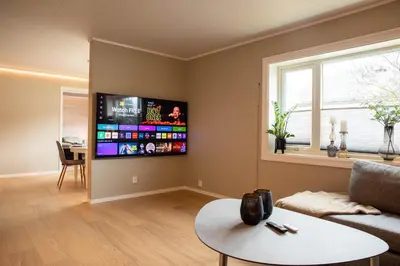 a living room with a couch and a tv on the wall at Huset på Plassen in Sogndal