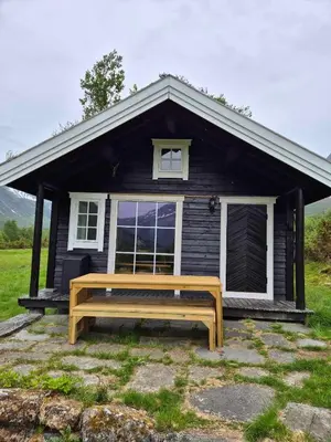 a wooden bench in front of a small house at Hytta på Kvia, Rognestøyldalen - Sæbø in Sæbø