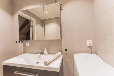 a bathroom with a sink and a mirror and a tub at Toppleilighet i sentrum av Lillehammer in Lillehammer