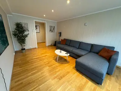 a living room with a blue couch and a table at Charming 3-Bedroom Apartment in the Heart of Kristiansund in Kristiansund