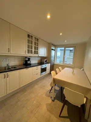 a kitchen with white cabinets and a table with chairs at Charming 3-Bedroom Apartment in the Heart of Kristiansund in Kristiansund