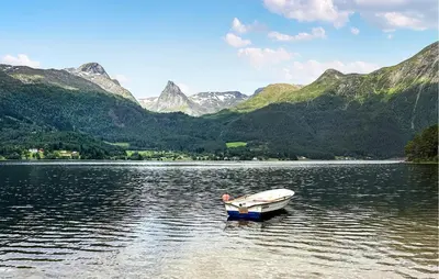 a boat on a lake with mountains in the background at Feriehus-Bjørkedal in Folkestad