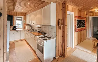 a kitchen with white appliances and wooden walls at Feriehus-Bjørkedal in Folkestad