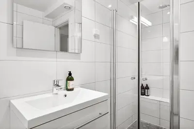 a white bathroom with a sink and a shower at Pergola - Free parking - 5 min walk to facilities in Bergen