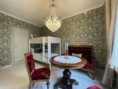 a room with a table and a bed and a chandelier at Jugend 1903 in Ålesund